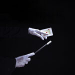 close-up-magician-performing-trick-playing-card-with-magic-wand-scaled (1)