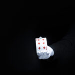 magician-s-hand-showing-diamond-playing-card-against-black-background